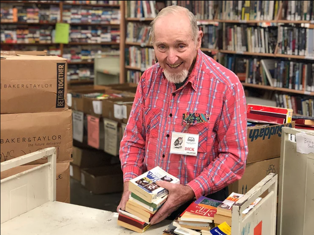 friends of the library volunteer sorting a pile of books