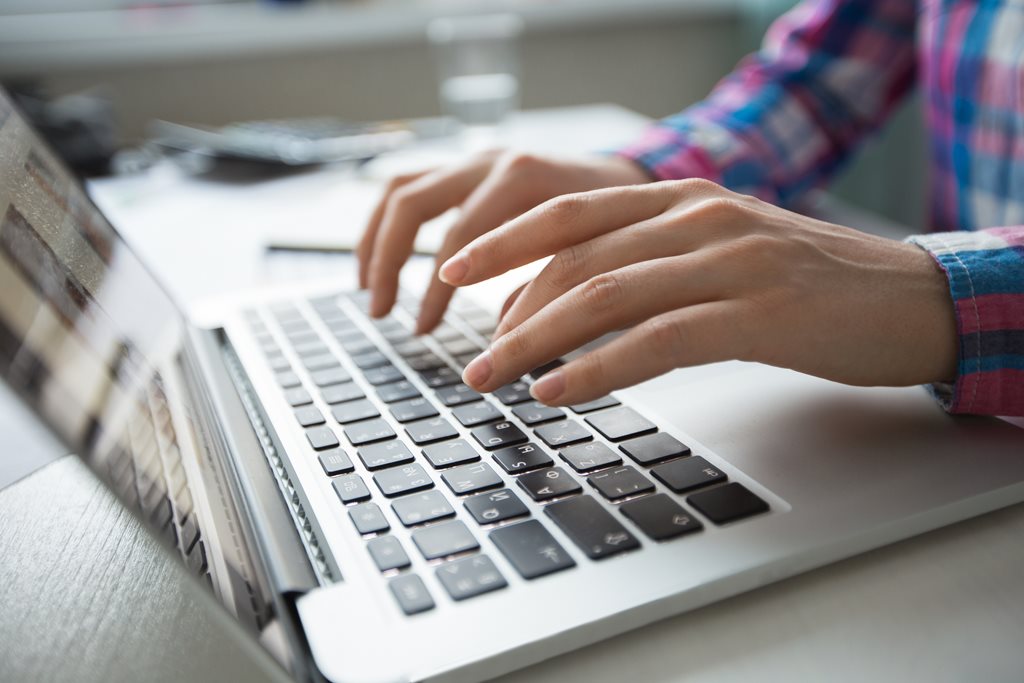 cropped view of hands typing on laptop computer