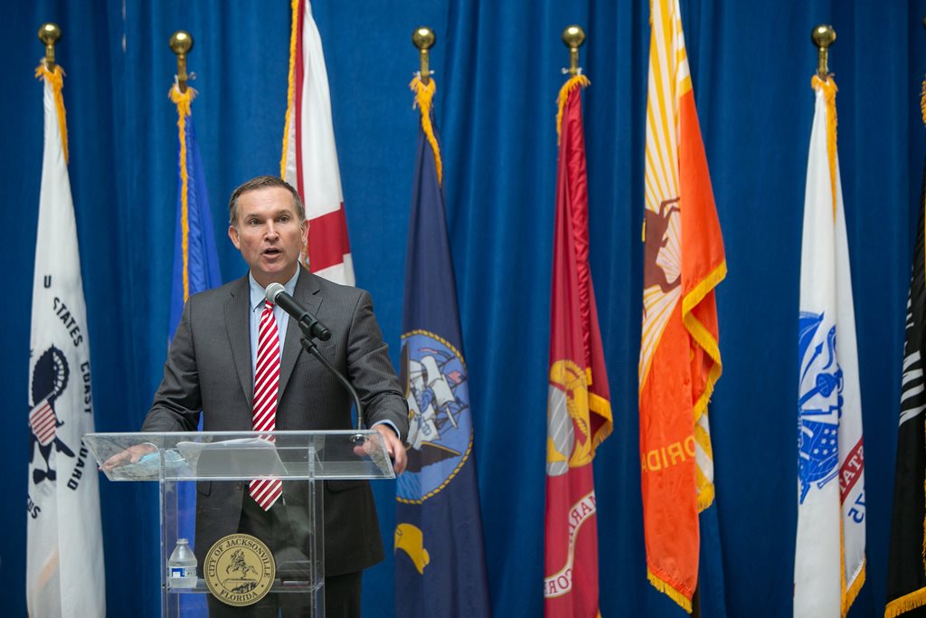 Mayor Curry speaking at podium in front of military flags