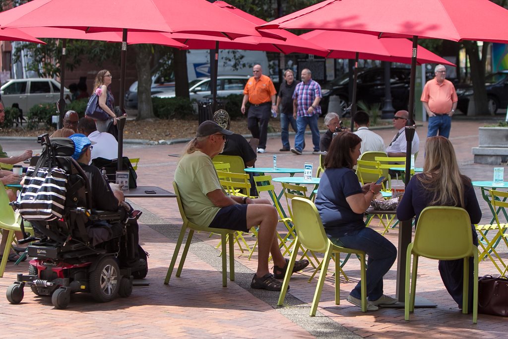 people sitting under the cover of umbrellas at hemming park