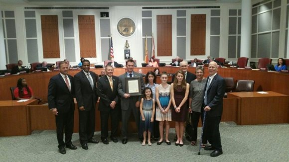 September 21, 2015 photo of Council Members Reggie Brown and Jim Love with John Holzbaur and his family in the City Council Chamber.