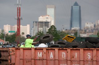 Photo of a worker loading tires into a roll-off container for disposal.