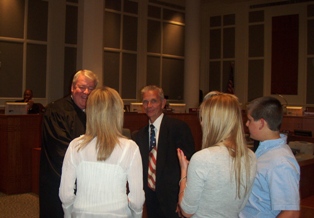 Photo of Council Member Doyle Carter's  family, wife Trish, daughter Heather, and son DJ, congratulating Council Member Carter with applause after he takes the Oath of Office from Chief Judge Donald Moran.