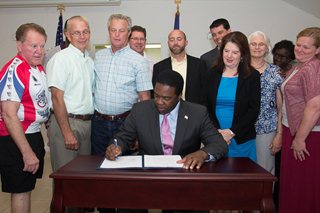 Photo of Mayor Alvin Brown signing the legislation as Council Members Don Redman, Doyle Carter, Greg Anderson and Lori Boyer, along with others, look on.