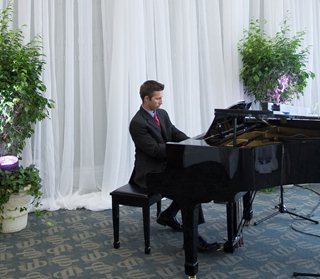 Photo of Walker Ellison playing the piano at the reception held in the Conference Hall at the Main Library after the installation ceremony.